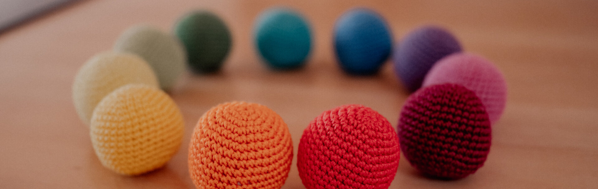 Bunte Stoffbälle auf einem Tisch, im Kreis angeordnet.
