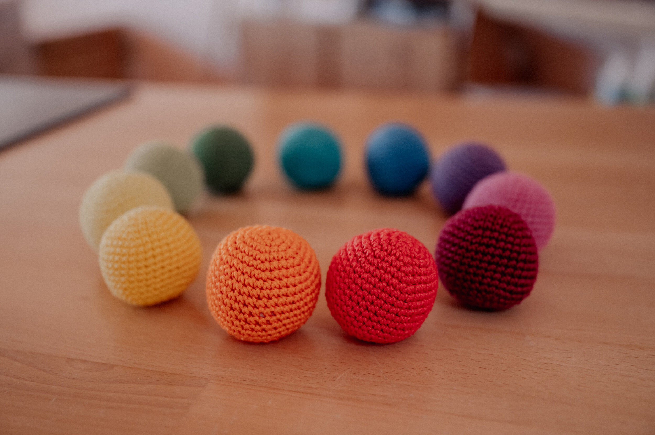 bunte-baelle-content-hort-kinderkrippe-parzival-zentrum-karlsruhe Bunte Stoffbälle auf einem Tisch, im Kreis angeordnet.